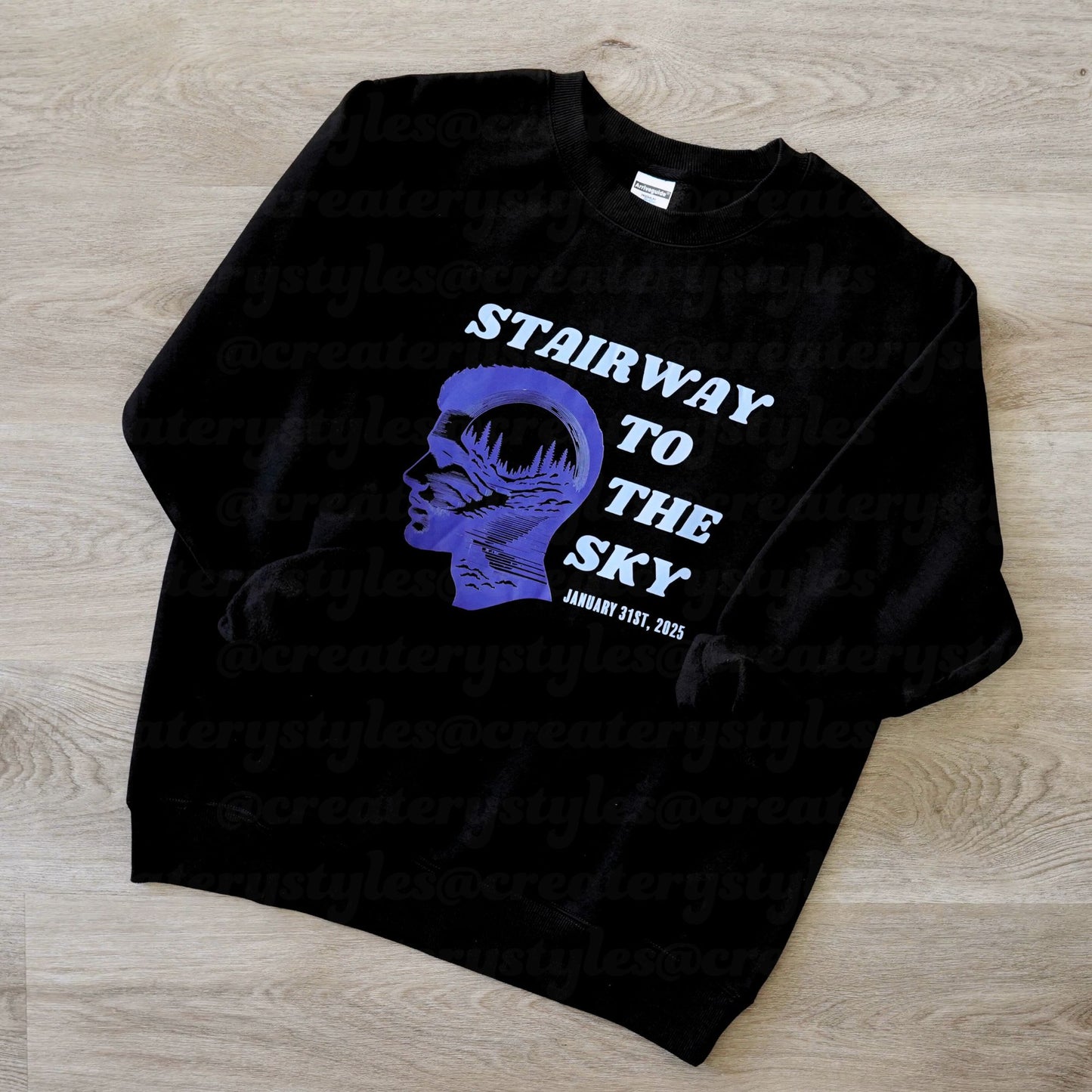 Black sweatshirt with blue graphic and text on a wooden surface