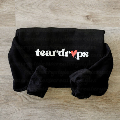 Black plush blanket with 'teardrops' text on a wooden surface