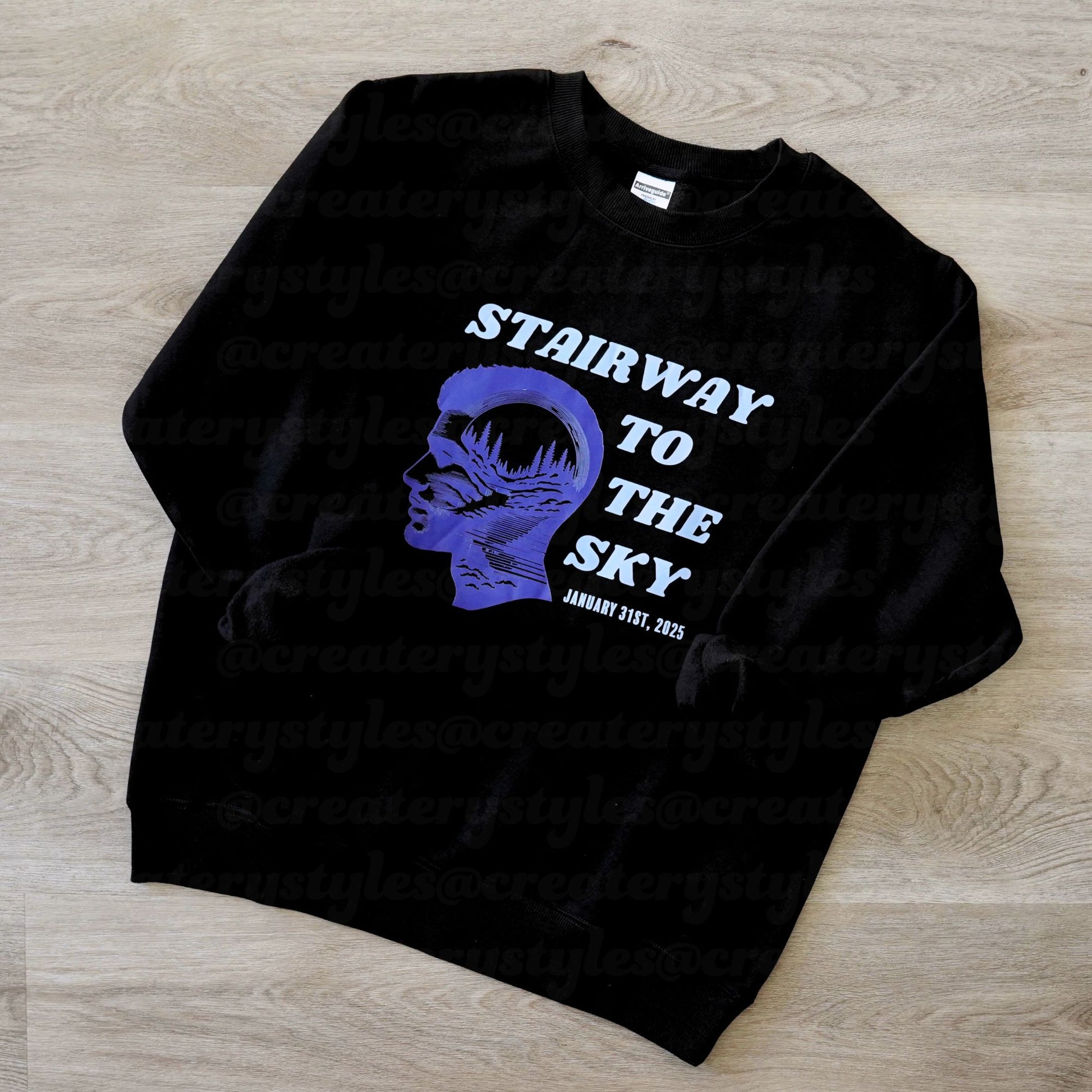 Black sweatshirt with blue graphic and text on a wooden surface
